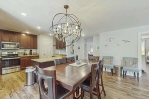 A spacious kitchen with wooden cabinets, a stainless steel oven, and a chandelier. - Dry Dock Condo Unit 204 (Myrtle Beach)