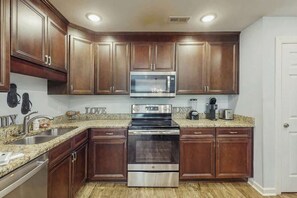 A kitchen with wooden cabinets, a stainless steel microwave, and an oven. - Dry Dock Condo Unit 204 (Myrtle Beach)