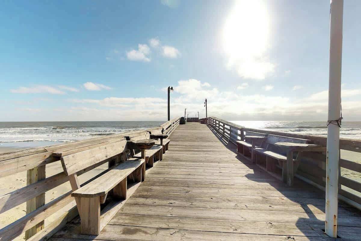 Une jetée en bois qui s’avance dans l’océan, avec des bancs et des garde-corps.