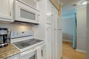 A kitchen with white appliances, including a stove, microwave, and refrigerator. - Best Beach Spot Oceanfront Condo (Surfside Beach)