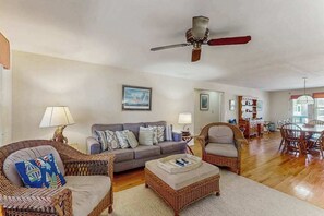 A living room with a sofa, two wicker chairs, a coffee table, a ceiling fan, and a dining area with a table and chairs. - Ocean Views at The Beach (North Myrtle Beach)