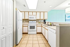 A compact kitchen with white cabinetry, a microwave, a stove, and a dishwasher. - The BW | Seven Oh Eight (North Myrtle Beach)