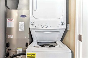 A front-loading washer and dryer unit with a Carrier brand air conditioner and a Coopers sticker on the wall.