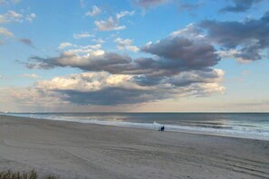 A beach with a wide sandy shore and a clear sky with clouds. - Sea Turtle Ocean View Condo (Myrtle Beach)