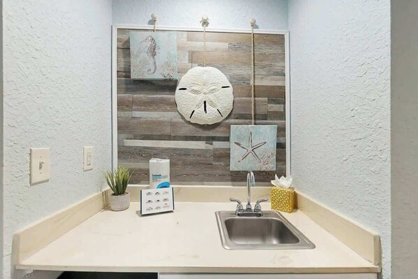 A bathroom with a sink, a mirror, and decorative wall art. - Sea Turtle Ocean View Condo (Myrtle Beach)