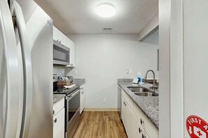 Eine kleine Küche mit Kühlschrank, Mikrowelle, Backofen und Spüle.