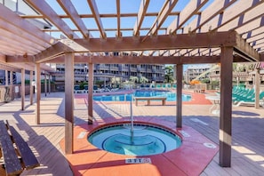A pool area with a wooden deck, lounge chairs, and a covered seating area. - Atlantic Escape Oceanfront Condo (North Myrtle Beach)