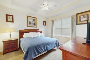 Un dormitorio con cama, mesita de noche, escritorio y ventilador de techo.