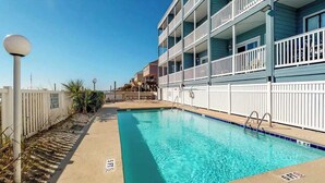 A swimming pool adjacent to a multi-story building with balconies. - Beachfront Blessing Oceanfront Condo (Garden City Beach)