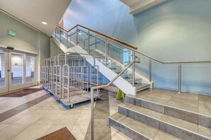 A modern interior with a glass-walled staircase, metal railings, and a tiled floor. - Sandy Beach Resort 304 (Myrtle Beach)