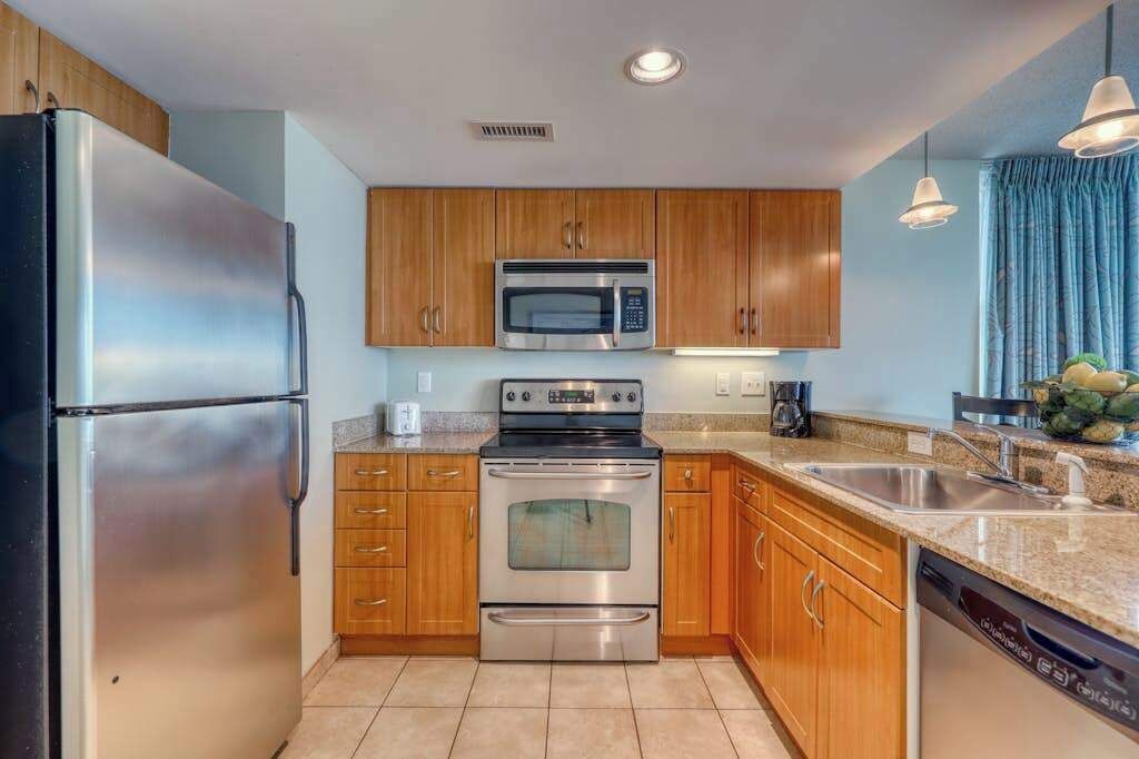 A modern kitchen with stainless steel appliances, wooden cabinets, and a granite countertop.