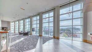 Eine großzügige Lobby mit hohen Fenstern, einem gemusterten Teppich und einer Treppe.
