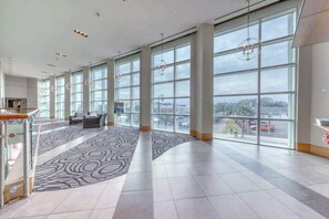 A spacious lobby with large windows, a patterned carpet, and a staircase. - Sandy Beach Resort 304 (Myrtle Beach)