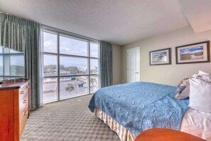Ein Hotelzimmer mit großem Fenster, einem Bett, einem Fernseher und einem Schreibtisch.