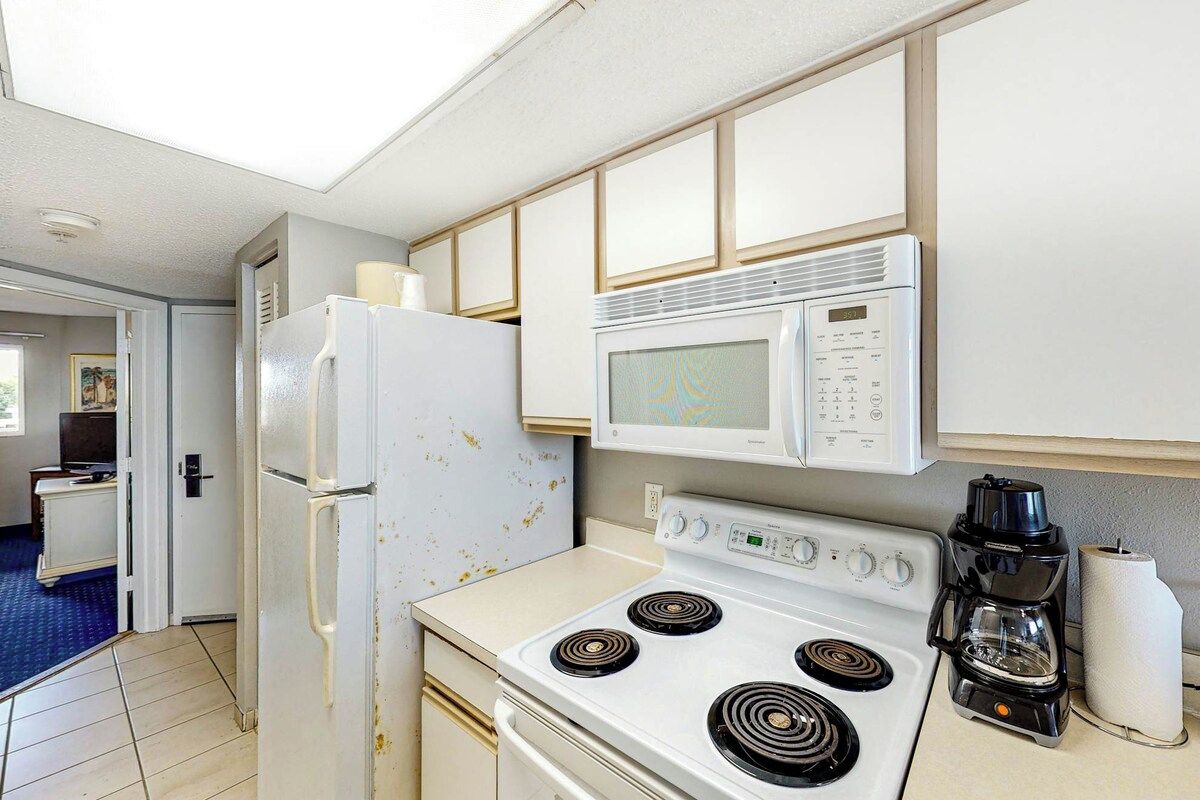 A kitchen with a white stove, a microwave, and a coffee maker.