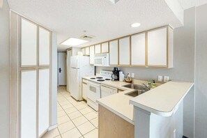 A kitchen with white cabinets, a microwave, stove, and sink. - Bay Watch Resort 0314 (North Myrtle Beach)