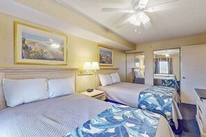 Une chambre d’hôtel avec deux lits, un ventilateur de plafond et des œuvres d’art accrochées aux murs.