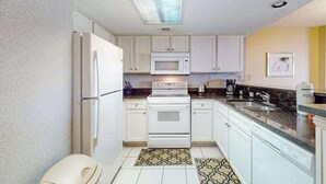 Una cucina compatta con mobili bianchi, un forno a microonde, un forno e un lavello.