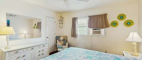 Une chambre à coucher avec un lit, une commode, une chaise et un ventilateur de plafond.