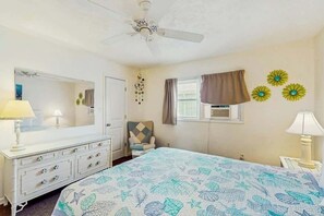 Ein Schlafzimmer mit Bett, Kommode, Stuhl und Deckenventilator.