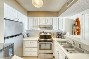 A modern kitchen with white cabinetry, stainless steel appliances, and a built-in oven. - Sands Beach Club 1127 (Myrtle Beach)