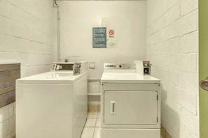 A laundry room with two washing machines and a dryer, a sign with instructions, and a door with a handle. - Sands Beach Club 1127 (Myrtle Beach)