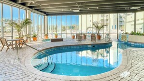 Una piscina interior amb aigua blava cristal·lina, envoltada per un solàrium amb rajoles i plantes en testos.