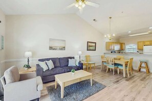 A modern living room with a sofa, coffee table, and dining area. - Magnolia North Unit 304 (Myrtle Beach)