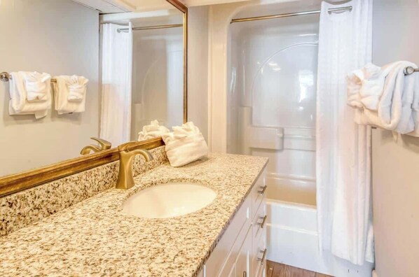 A bathroom with a granite countertop sink, a mirror, and a shower area. - Oceanfront Seaside Retreat (Litchfield Beach)