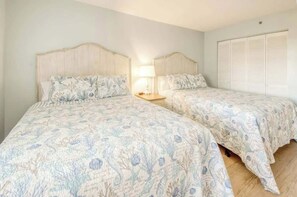Ein Schlafzimmer mit zwei Betten, einem Nachttisch, einer Lampe und einem Kleiderschrank.