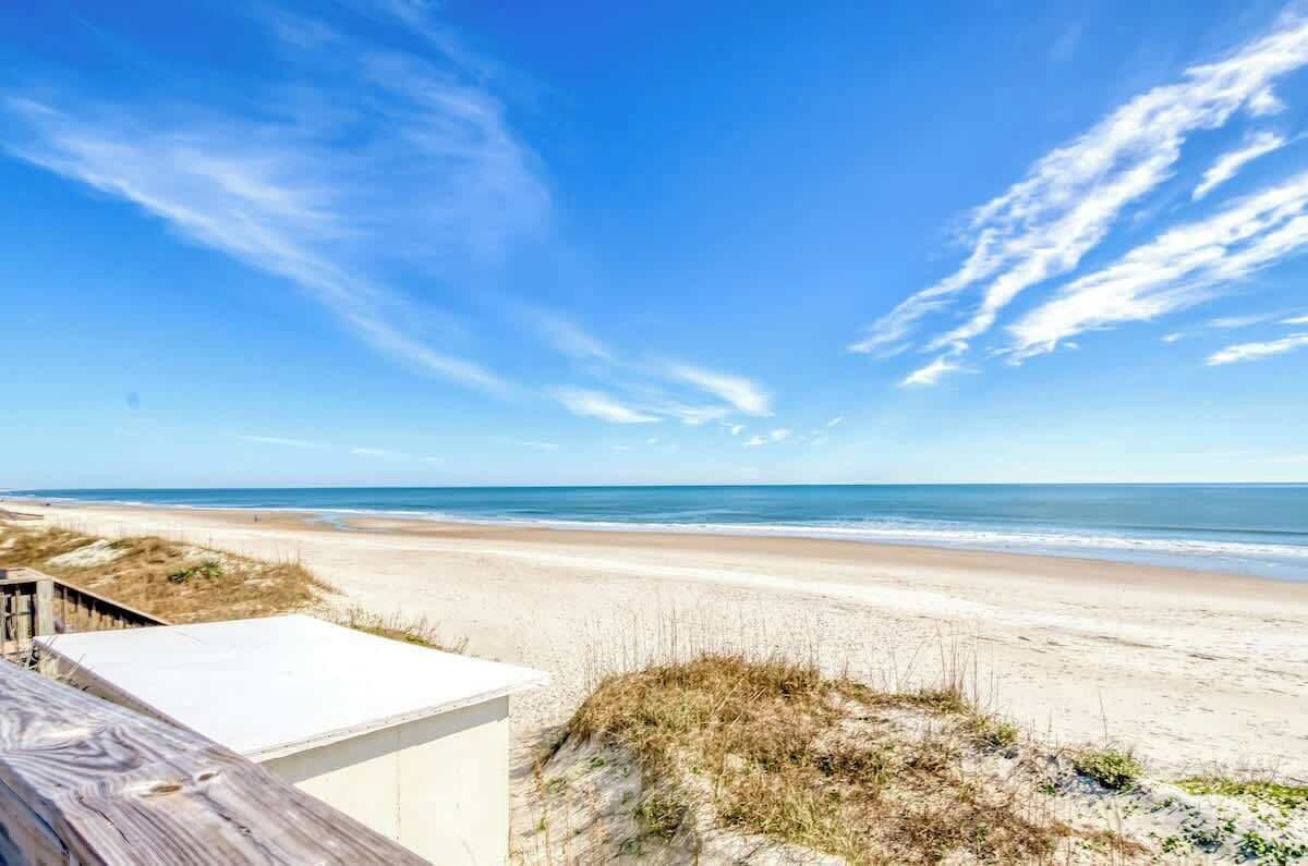 Une vue sur la plage avec une terrasse en bois et une plage de sable.