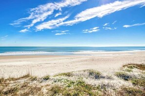 Ein Strand mit Dünen und blauem Himmel.