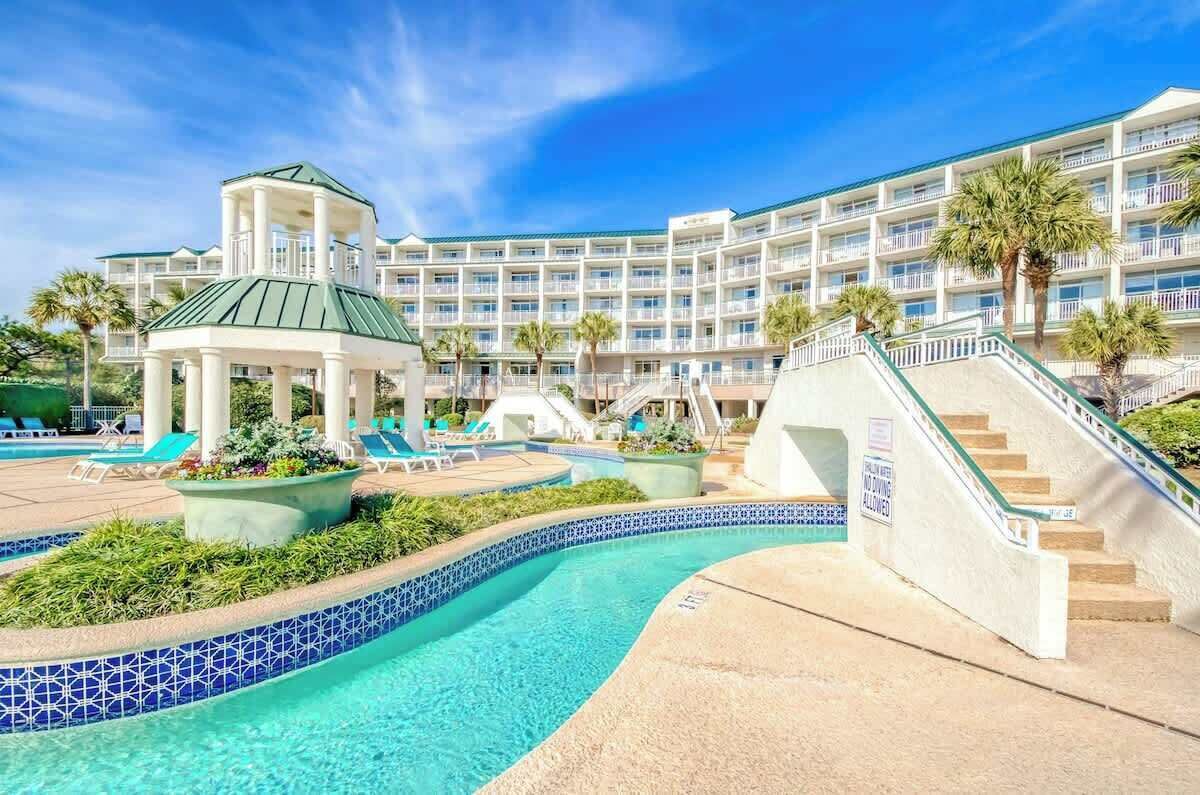 A hotel with a pool, a gazebo, and a multi-story building with balconies.