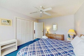 A bedroom with a bed, a ceiling fan, a bedside table with a lamp, a dresser, and a bench. - Stillwater Family Home (Myrtle Beach)