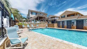Ein Pool mit Liegestühlen und einer Treppe, die zu einem Gebäude führt.