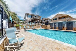 Ein Pool mit Liegestühlen und einer Treppe, die zu einem Gebäude führt.