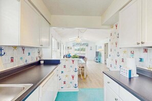 A kitchen with white cabinets, a central island, and nautical-themed wall decorations. - Stillwater Family Home (Myrtle Beach)