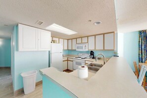 Een moderne keuken met een centraal eiland, witte kastjes, een magnetron en een fornuis.