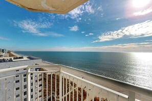 A coastal view from a balcony overlooking a beach with a clear sky. - Bay Watch Resort 1202 (North Myrtle Beach)