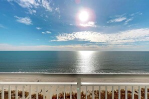 A beach view with a wooden railing in the foreground.