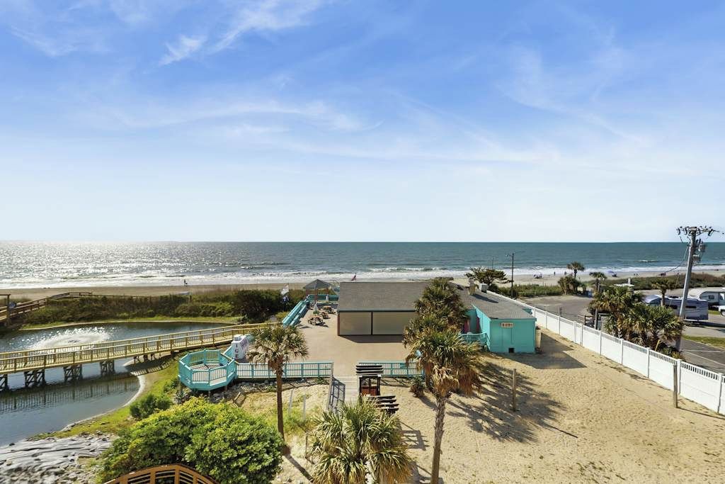 Une vue sur la plage avec une promenade en bois, un petit bâtiment et un ciel dégagé.