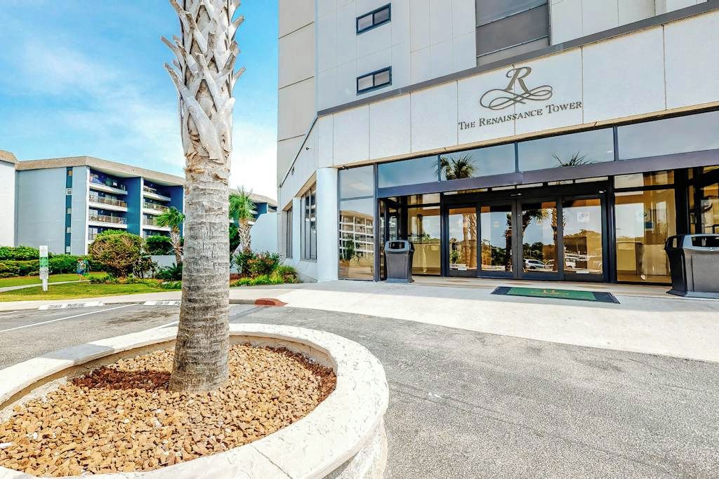 Une entrée d’hôtel moderne, avec un palmier au premier plan et une enseigne indiquant « The Renaissance Tower ».