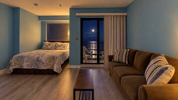 A bedroom with a bed, a sofa, and a view of the balcony.