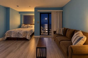A bedroom with a bed, a sofa, and a view of the balcony. - Sunrise at Renaissance | Luxe Escape (Myrtle Beach)