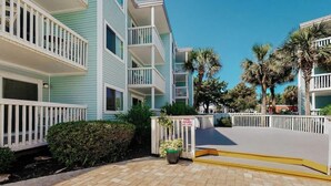 A multi-story building with balconies, a pool area, and palm trees. - Ocean Retreat Unit N1 (North Myrtle Beach)