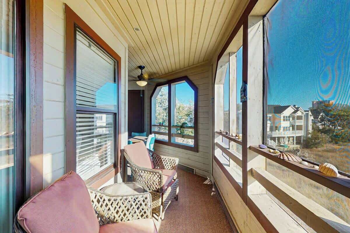 Eine überdachte Veranda mit Korbmöbeln und Blick auf benachbarte Gebäude.