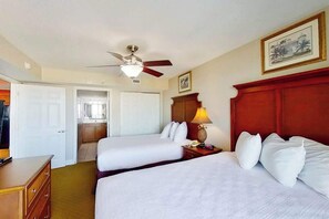 A hotel room with two beds, a ceiling fan, a lamp, and a framed picture on the wall. - Bahama Sands Unit 0701 (North Myrtle Beach)