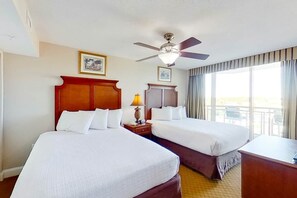 A hotel room with two beds, a ceiling fan, a desk, and a window with curtains. - Bahama Sands Unit 0701 (North Myrtle Beach)