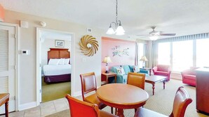 A hotel room with a bed, a dining area with a table and chairs, a living area with a sofa, and a ceiling fan. - Bahama Sands Unit 0701 (North Myrtle Beach)