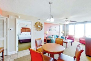 A hotel room with a bed, a dining area with a table and chairs, a living area with a sofa, and a ceiling fan. - Bahama Sands Unit 0701 (North Myrtle Beach)